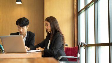 Patronuyla toplantı odasında tekerlekli sandalyedeki iş kadınının görüntüsü. İş yerinde engelli kişi