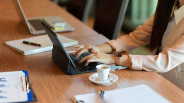 Portatif tablet üzerinde çalışan bir iş kadınının kırpılmış görüntüsü. Şirket toplantı odasında buluşurken klavyede yazan bir kadın asistan..