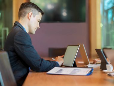 Başarılı iş adamı, iş arkadaşıyla konferans odasında görüşürken dijital tablet üzerinde çalışıyor.