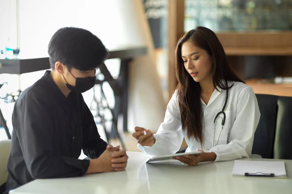 アジアの女性医師が診療所で男性患者に医療アドバイスを行う — ストック写真