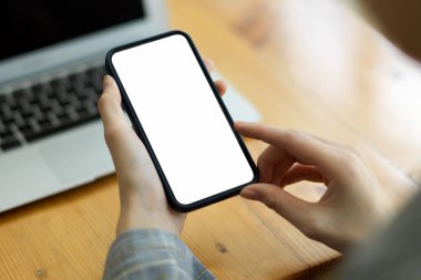 Mesaj için akıllı cep telefonu kullanan yakın plan kadın ve arka planda bulanık internet çalışma alanına göz atın. Cep telefonu boş ekran modeli