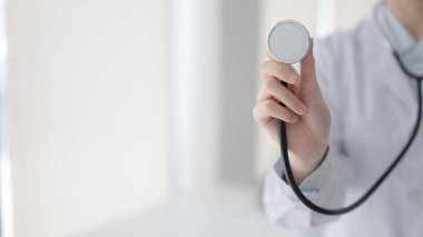 Doktorun elini tutarken ya da beyaz teşhis odasında, hastanede ya da klinikte dururken siyah steteskopu gösterirken..