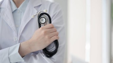 Doktorun elini steteskopla tutarken beyaz teşhis odasında, hastanede ya da klinikte kolları çapraz dururken kapat..