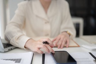 İş kadını ya da ofis çalışanı elinde dolma kalemle ofiste çalışırken telefona bakıyor. Sekreter ya da Yazman, Modern şirket..