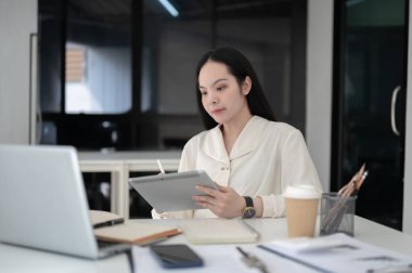 İş kadını ya da ofis çalışanı Stylus 'u elinde tabletle ofiste otururken düşünüyor. Sekreter ya da Yazman, Modern şirket..