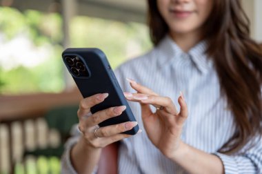 Kafede otururken mavi çizgili tişörtlü uzun tırnaklı bir kadının akıllı telefonuna bakıp daktilo yazması. Dışarısı Ürpertici.