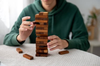 Kule inşaatında tek başına oynarken adamın ellerini kapat ve tahta bloklardan bir parça al. Parti oyunu, geliştirme oyuncakları, öğrenme etkinliği.