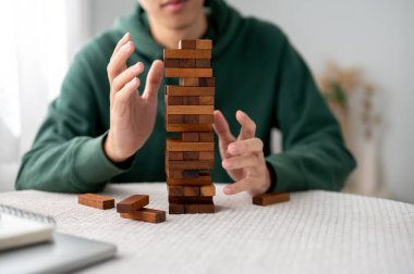 Elleri havada, kule inşaatı oyununun ahşap bloklarını tek başına oynayan bir adama yaklaş. Parti oyunu, geliştirme oyuncakları, öğrenme etkinliği.