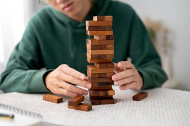 Bir adam tek başına oynarken kule inşaatında tahta bir bloktan bir parça alıp götürüyor. Parti oyunu, geliştirme oyuncakları, öğrenme etkinliği.