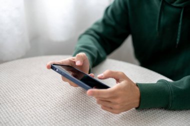 Adam ellerini kapatır, telefonda yatay olarak oyun oynar, kafede ya da evde video izleriz. Akıllı telefon kullanıcıları, Modern Teknoloji, Şehir Hayatı.