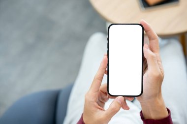 Bir kafede ya da kütüphanede otururken iki eliyle beyaz ekran akıllı telefonu tutan bir çift el. Modern Teknoloji, Şehir Hayatı, Reklam Model.