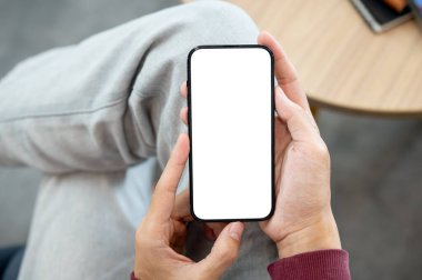 Boş ekran akıllı telefonu tutan çapraz bacaklı bir adam. İki eli de kafeteryada ya da kütüphanede oturuyormuş gibi. Modern Teknoloji, Şehir Hayatı, Reklam Model.