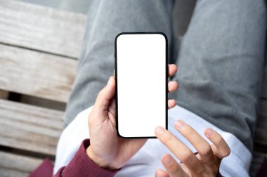 Bir adamın elleri boş ekran akıllı telefonu tutarken parmakları dışarıda, ahşap bankta oturuyordu. Modern Teknoloji, Şehir Hayatı, Reklam Model.