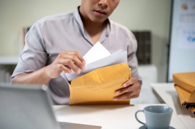 Elinde bir zarf olan işadamının bilgisayarı ve kahveyi bir kenara bırakıp belgelere bakması. Şirket işleri, Modern Şirketler, Çalışma Saatleri.