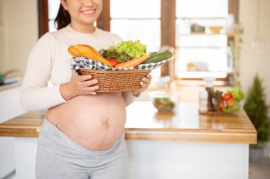 Mutfakta dikilen salata yapmak için elinde taze sebze sepeti ve ekmek tutan hamile kadına yakın durun. Doğum öncesi bakım, Hamilelik Diyet yemeği.