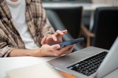 Kafedeki masada otururken dizüstü bilgisayarla ve defterle el ele tutuşup telefona dokunan bir adamın fotoğrafını çek. Çalış ya da çalış, dışarı çık..