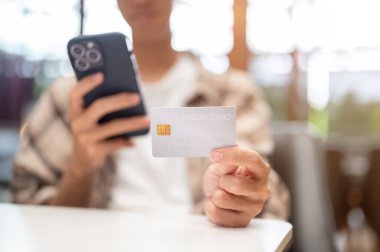 Akıllı telefona bakan, elinde tutan ya da kafedeki masada otururken kredi kartını gösteren adama yaklaş. Nakitsiz ödeme, seyahat kartı, banka reklamı..