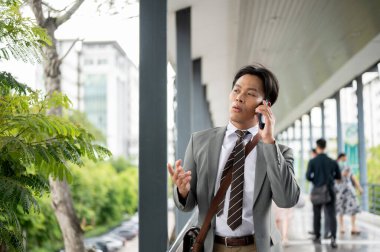 İş adamı ya da ofis çalışanı yaya köprüsünde yürürken bir müşteriyle telefonda konuşuyor. Git ya da işi bırak, modern şirket işleri..