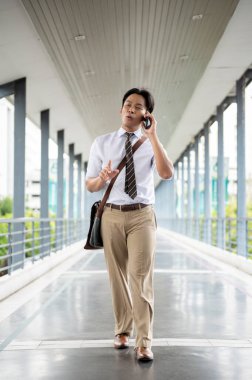 İş adamı ya da ofis çalışanı yaya köprüsünde yürürken telefonuyla mutlu bir şekilde konuşuyor. Git ya da işi bırak, modern şirket işleri..