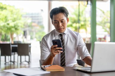 Ofis çalışanı ahşap masada dizüstü bilgisayarla telefona bakıyor ve bir kafede ya da kahve dükkanında kitap okuyor. İş adamı ya da Maaşçı, dışarıda çalışıyor..