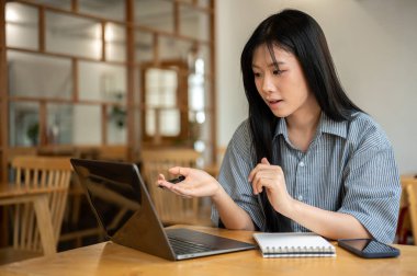Asyalı kadın konuşuyor ya da elleriyle anlatıyor ve kafenin ahşap masasında dizüstü bilgisayarına ve telefonuna bakıyor. Çalışıyorum ya da çalışıyorum. Dışarısı Ürpertici.