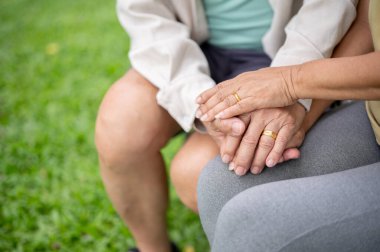 Parkta otururken altın alyanslarla yaşlı adamın ve kadının ellerini birbirine kenetleyin. Yaşlı çift, Yeşil Doğa, Serinleyen Açık Hava.