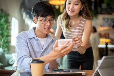 Asyalı bir kadın, kafeteryada ya da matarada hesap makineli bir adama yardım ediyor. Çalışma ya da öğrenim, Görev ya da Grup Projesi.