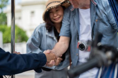 Turist, Tuk Tuk 'ta üç tekerlekli taksiyle şehri gezdikten sonra karısını bir kenara itiyor. Seyahat Etkinlikleri, Tayland taşımacılığı.