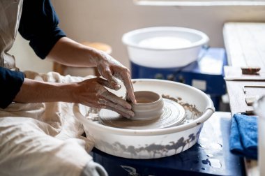 Çanak çömlek sanatçısının ellerini kapayın. Sınıfta ya da stüdyoda kil kase yüzeyi düzleştirin. Seramik Yapım, El yapımı Ürün, Sanat Atölyesi.