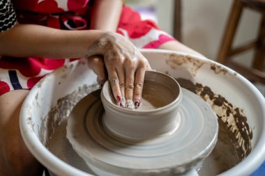 Boyanmış çivili çömlek sanatçısı. Sınıfta ya da stüdyoda dönen çarkta kilden bir kase yapıyor. Seramik Yapım, El yapımı Ürün, Sanat Atölyesi.