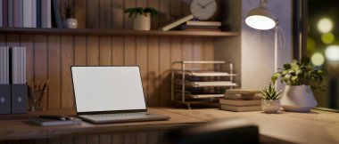 Boş ekran dizüstü bilgisayar ve lamba ışığının altında loş oturma odasında ya da ofiste ahşap masanın üzerinde kitap. Çalışma ya da Çalışma, Ad modeli, 3B Yapılandırma, 3B Resim.