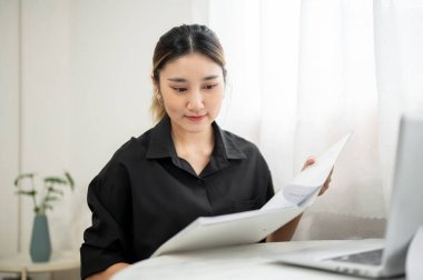 Asyalı iş kadını ya da ofis çalışanı dosya klasörüne bakıyor ya da çalışma masasında belge okuyor. Modern Şirket, Şirket işi, İş Gelişigüzel.