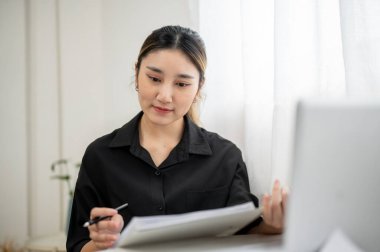 Zeki Asyalı iş kadını ya da ofis çalışanı çalışma masasında elinde kalem ve klasör okuma belgesi tutuyor. Modern Şirket, Şirket işi, İş Kayıpları.