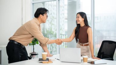 İş adamı ya da ofis çalışanı çalışma masasında dizüstü bilgisayarın yanında bir kadınla el sıkışıyor. Ortaklık anlaşması, yaratıcı işler, günlük iş..