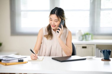 Ofisteki masada telefonla konuşurken elinde kalem tutan güzel bir ofis çalışanı. İş Gelişigüzel, Modern Şirket, Şirket İşi.