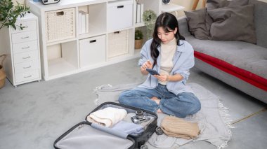 Seyahat Gezisi, Turist Çantası, Çanta Düzenleme. Yatak odası ya da oturma odasındaki bavulları düzenlerken ya da paketlerken telefona bakan bir kadın..