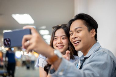 Asyalı turist çiftler havaalanında beklerken telefonla fotoğraf çeken gezgin kadınlara gidiyorlar. Yurtdışına seyahat, hava yolcusu, tatil tatili.