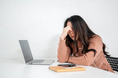 Sınıf ya da ofis masasında dizüstü bilgisayarının önünde şakağına masaj yapan yorgun Asyalı kadın. Çalışma ya da Eğitim, Şehir Hayatı, Modern Teknoloji.