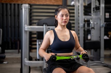 Asyalı kadın fitness eğitmeni ya da spor salonunda germe aletleriyle egzersiz yapan bir müşteri. Kas geliştirme, egzersiz, sağlıklı yaşam.