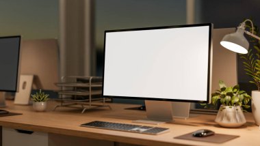 Loş ışıklı ofis odasındaki ahşap çalışma masasında saksı bitkisi ve masa lambası olan beyaz ekran bilgisayar. Reklam Biçimi, 3B Yapılandırma, 3B illüstrasyon.