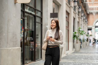 Alışveriş merkezinde ya da markette yürürken elinde kahve poşeti olan mutlu Asyalı kadın önüne bakıyor. Boş zaman, Solo gezi, Seyahat Turisti.