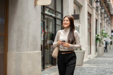 Alışveriş merkezinde yürürken elinde kahve poşeti olan güzel Asyalı kadın önüne bakıyor. Boş zaman, Solo gezi, Seyahat Turisti.