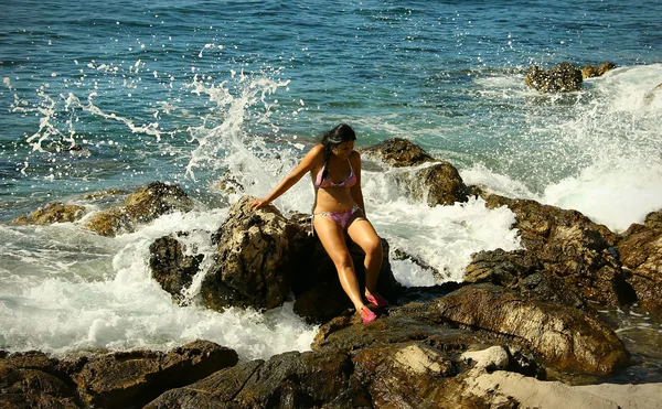 Mujer de pelo oscuro se sienta en las rocas en la fiebre del agua —  Fotos de Stock
