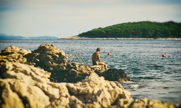 Людина сидить на природні Jetty — стокове фото