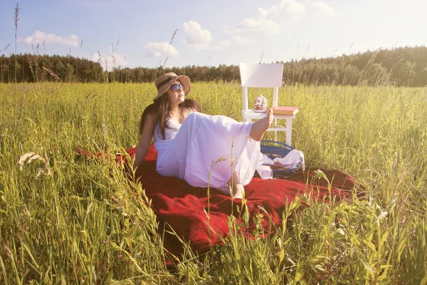 Femme assise sur une couverture rouge au coucher du soleil — Photo