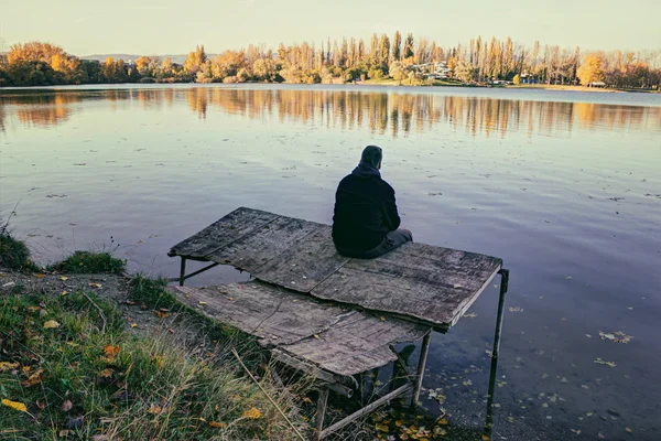 Muž z zad sedící na dřevěném molu — Stock fotografie