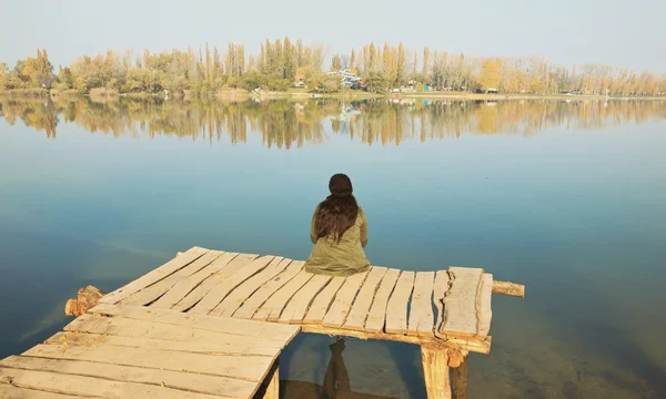 Žena sedí na dřevěné krtek — Stock fotografie