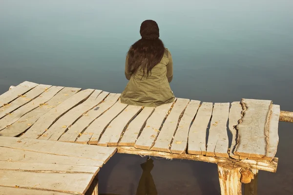 Kobieta siedzi w Mola drewniane — Zdjęcie stockowe