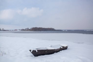 Gölün karlı kıyısında karla kaplı bir tekne..