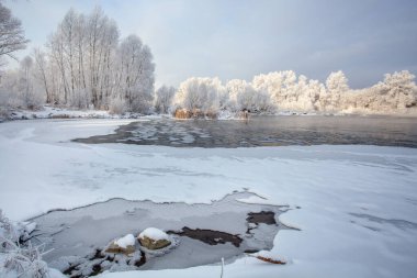 Nehirde soğuk bir kış günü. Buz kütleleri açık sularda yüzer. Kıyıdaki ağaçlar buzla kaplı..